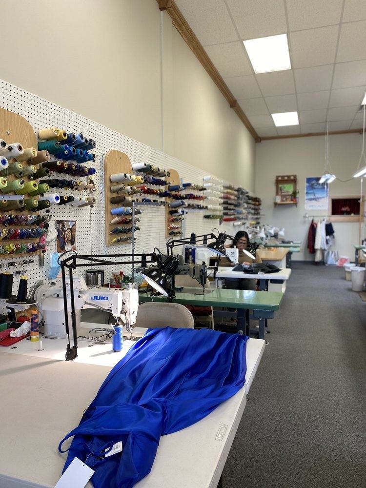 Inside the Perfect Alterations workroom: sewing station and a wall of thread spools